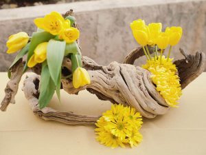yellow tulips and carnations with drift wood make a beautiful table centerpiece