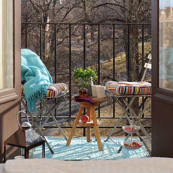 light turquoise area rug and throw with bright striped cushions