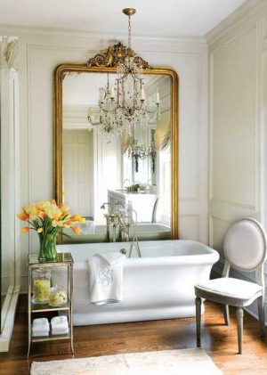golden large wall mirror and white tub with yellow flowers in modern bathroom