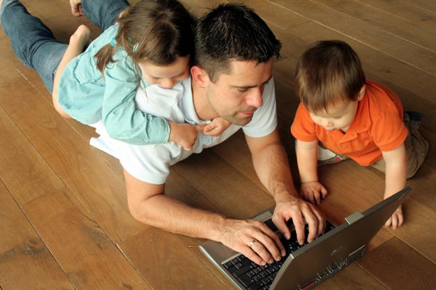 father and kids looking at laptop